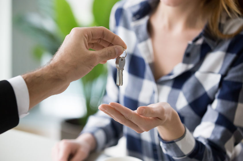 Young woman getting keys to new apartment from realtor