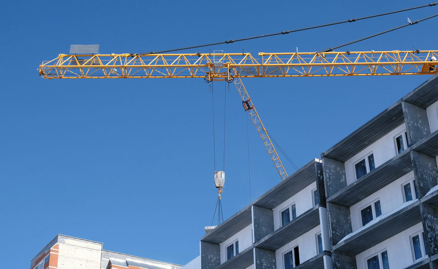 Construction site with cranes on sky background. The Builder works on the roof of a multi-storey building.