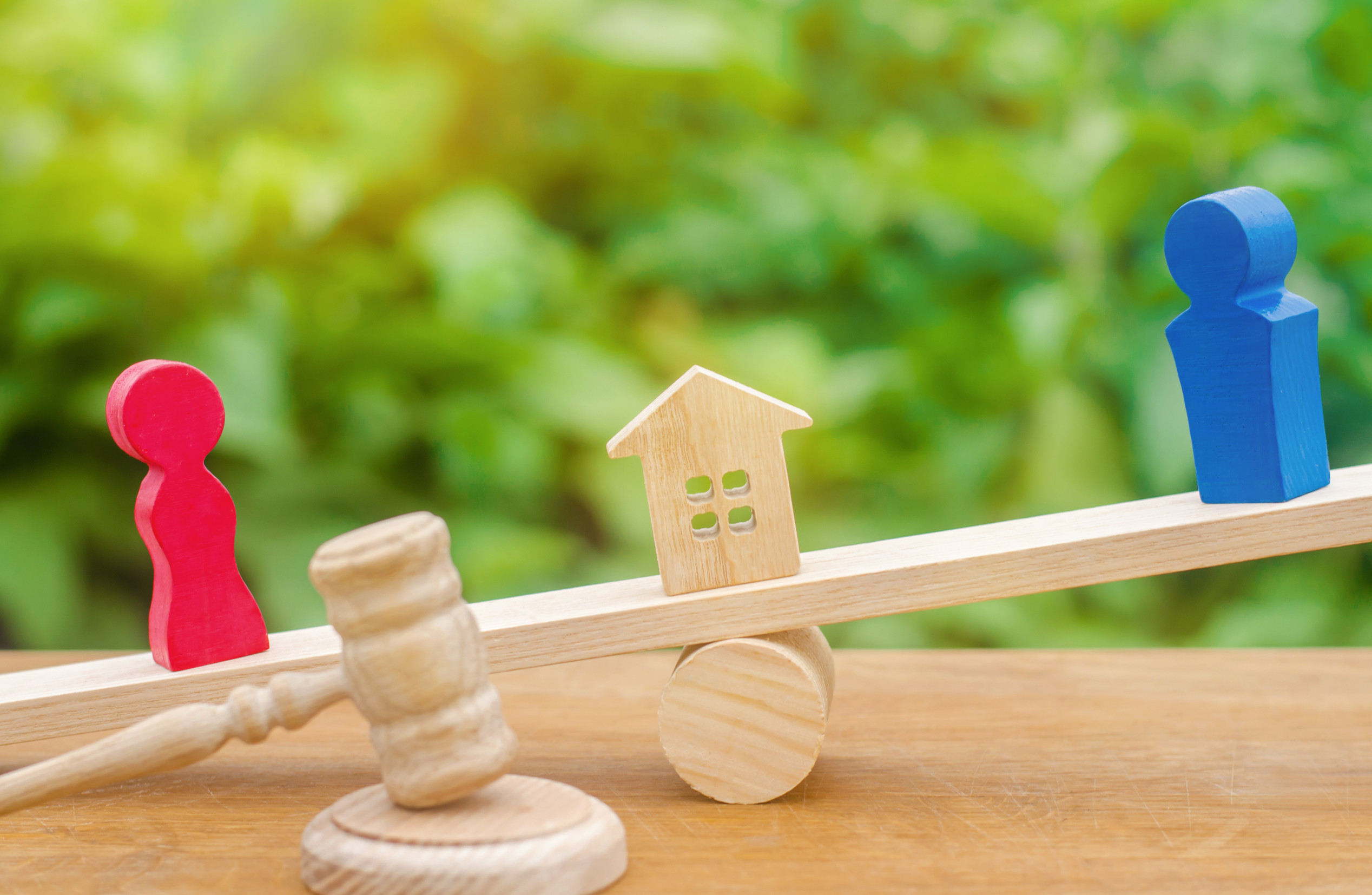 division of property by legal means. clarification of ownership of the house. wooden figures of people. man and woman are standing on the scales. trial, conflict. court. divorce