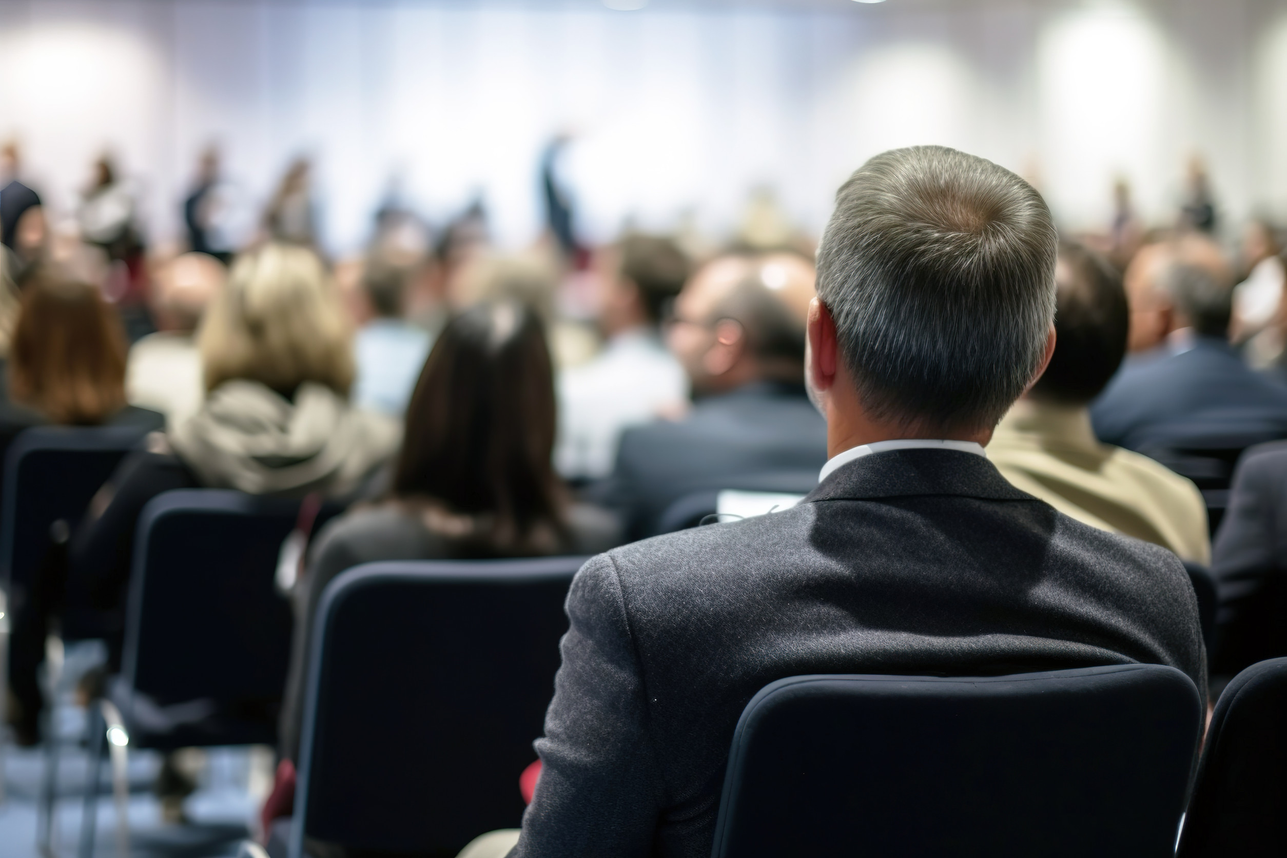 Beck view of man in audience at business conference. Focus on foreground. Generative AI