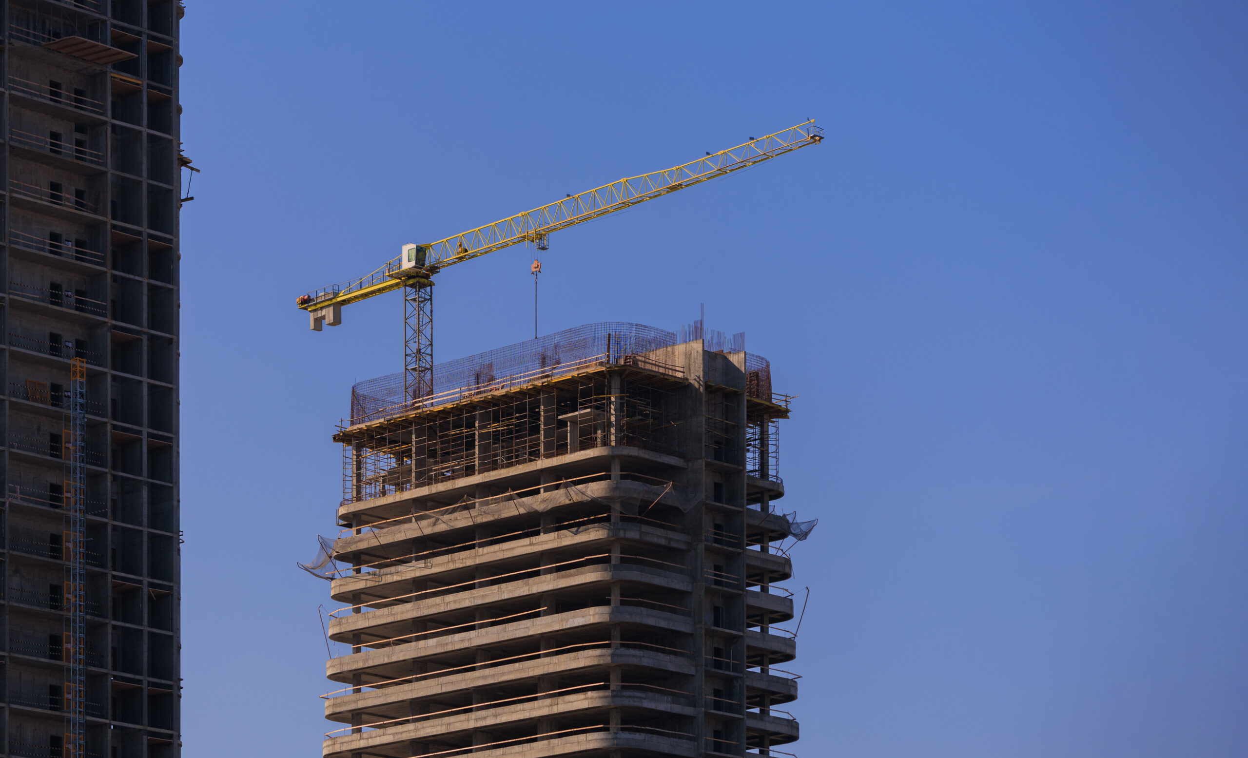 Construction of buildings and high-rise cranes against the evening sky